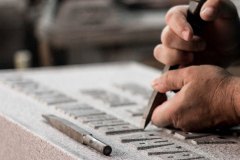 Photo of memorial maker hand carving lettering into stone